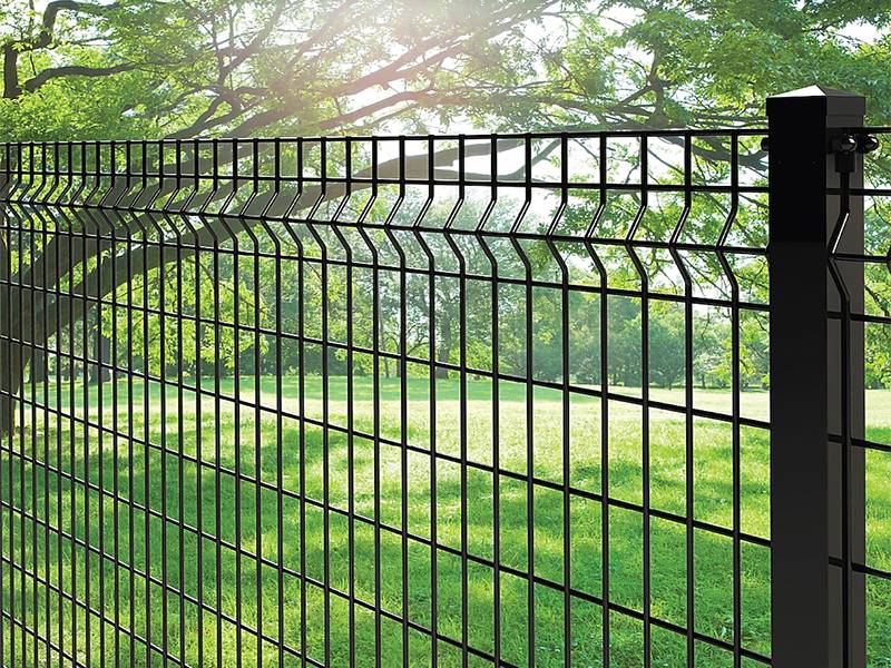 Green leaves and grass in the park can be seen through the black PVC coated 3D security fence