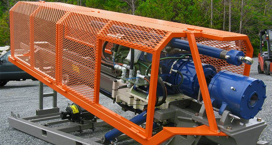 Orange expanded metal machine guards are installed on the drilling equipment.