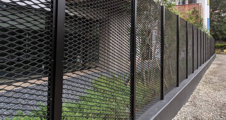 Black expanded metal mesh fence is installed along the residential community.