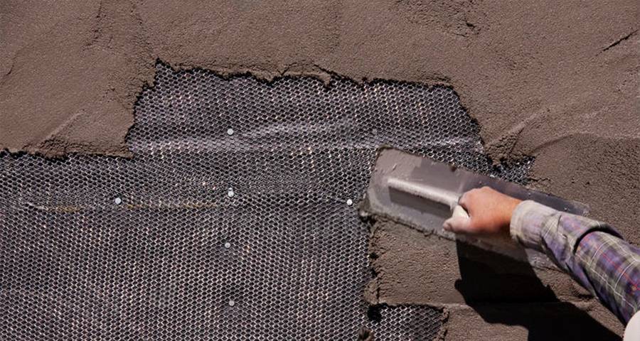 A worker is plastering a wall to which expanded metal lath has been fixed