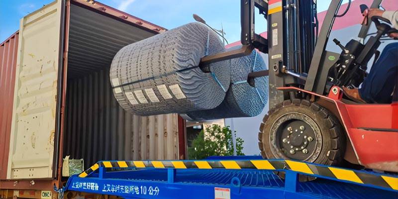 Workers are using a forklift to load line wire crimped wire mesh roll into the container.
