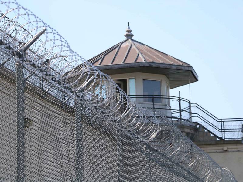The watchtower can be seen through the razor wire prison fence