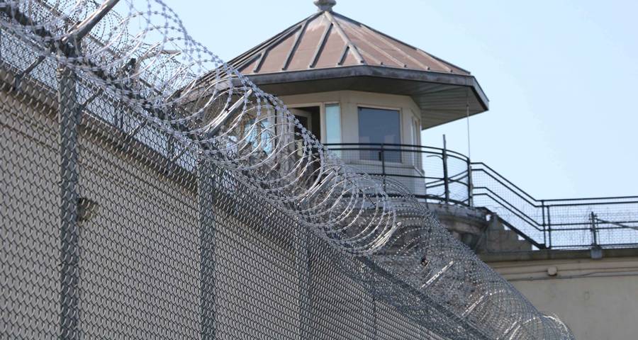 The watchtower can be seen through the razor wire prison fence