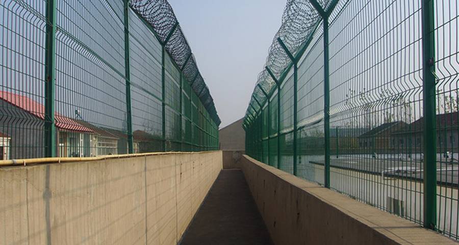 The combination of razor wire and welded wire fence is installed on both sides of the prison patrol road.