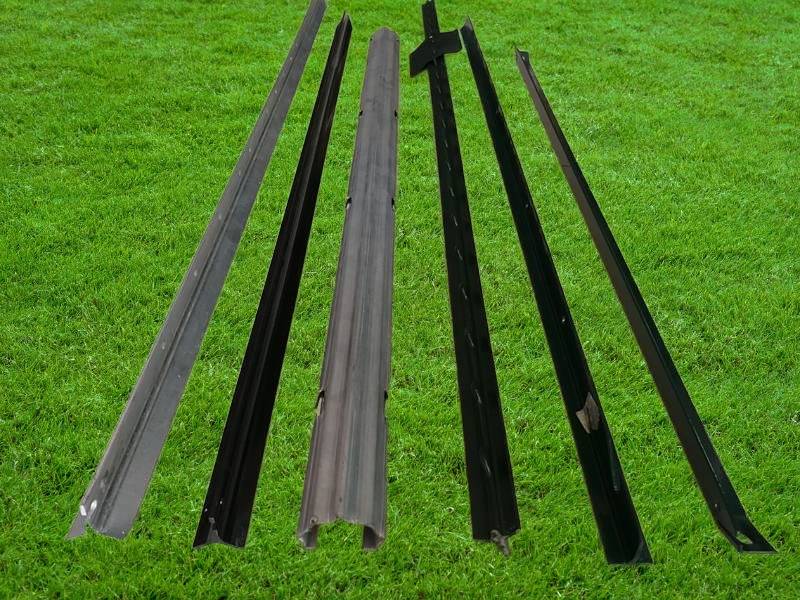 Six different types of steel farm fence posts on the grass